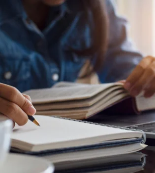 A girl carefully making notes for academic content writing services in India from a book