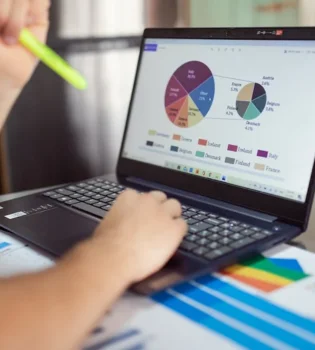 A person studying an infographic design presented as a pie chart while using a laptop