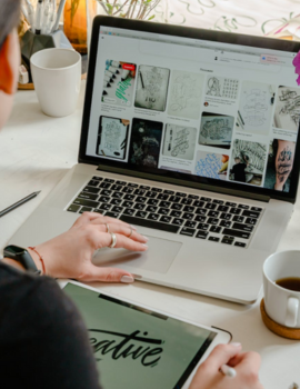 A woman quickly doing product descriptions content writing on her laptop with a pen and tablet.