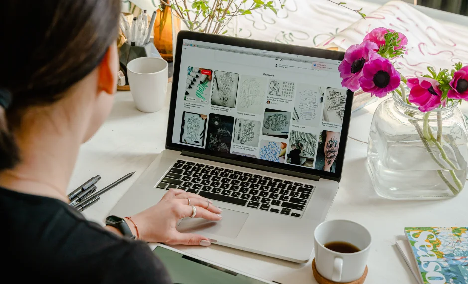 A woman is typing on her laptop with a floral backdrop, engrossed in content writing and creating.