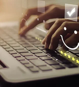 A person working on tech product descriptions writing on a laptop with a smiley face sticker.