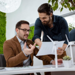 Two men working together in an office, deeply focused on a document, talking about the project